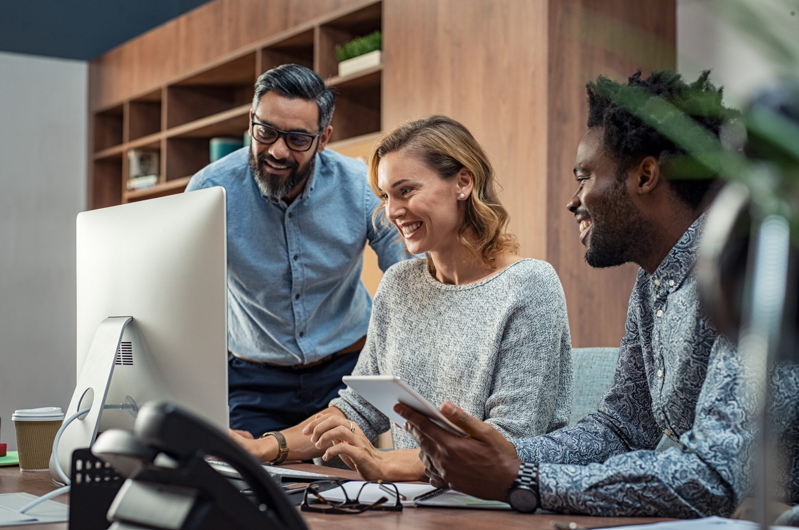 Casual businessmen and cheerful business woman in office working on a project together. Happy business man and colleagues working in a creative company. Mature businesswoman with her team working together on presentation for business meeting in office.